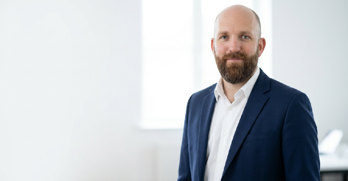Ben Browning, founder of Resonant, in a navy blazer and white shirt in a modern office